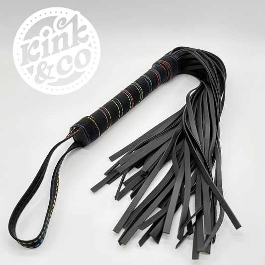 Black faux leather BDSM flogging whip with rainbow stitching spiral on the handle. Grey background with kink and co logo in the top left 