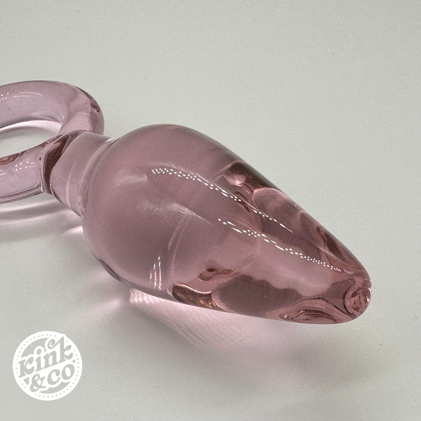 Tapón anal de cristal rosa con forma de lágrima y mango de aro